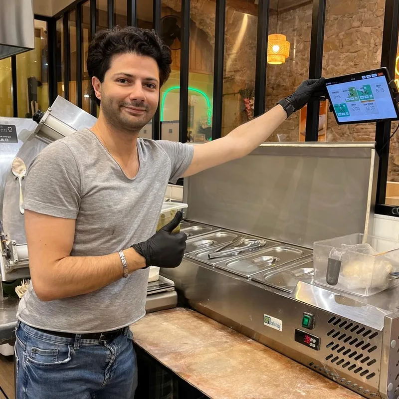 Serge Menassa, co-founder of CookOnTime and restaurant owner, showing the app on the kitchen tablet at his restaurant's pass